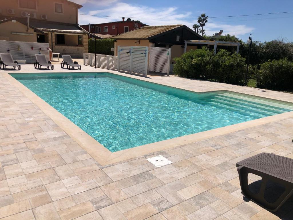 a swimming pool with blue water in a yard at Casa Zagara in Avola