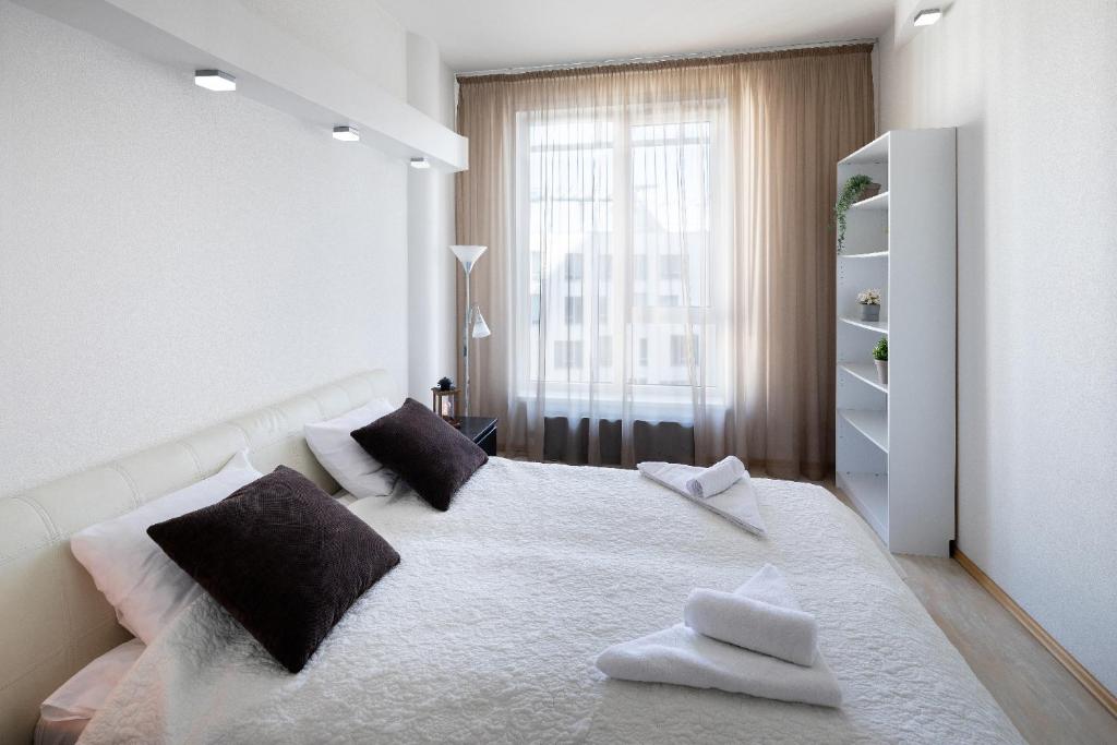 a white bedroom with a large bed with two pillows at Riga Riverside One Bedroom Apartment in Riga