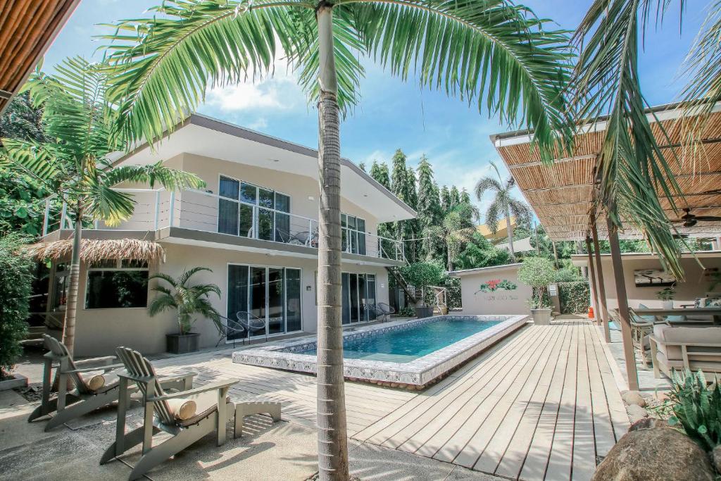 a house with a swimming pool and a palm tree at Tamarindo Bay Boutique Hotel - Adults Only in Tamarindo