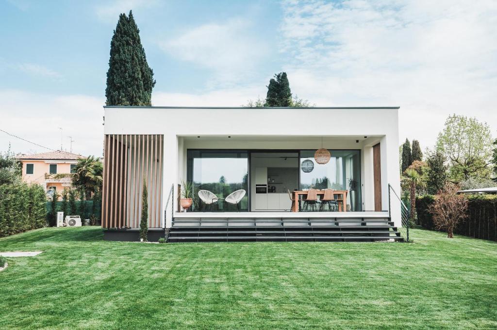 una piccola casa bianca con un cortile verde di Boutiquehouse Montelino a Bardolino