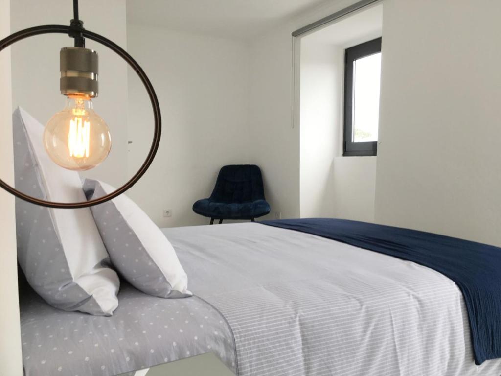 a bedroom with a bed with a lamp and a chair at Azores Black Mountain House, Estúdio e T2 Ilha do Pico in São Roque do Pico