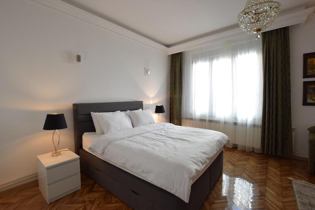 ein Schlafzimmer mit einem großen Bett und einem Kronleuchter in der Unterkunft Crown apartment - Your most comfortable stay in Belgrad