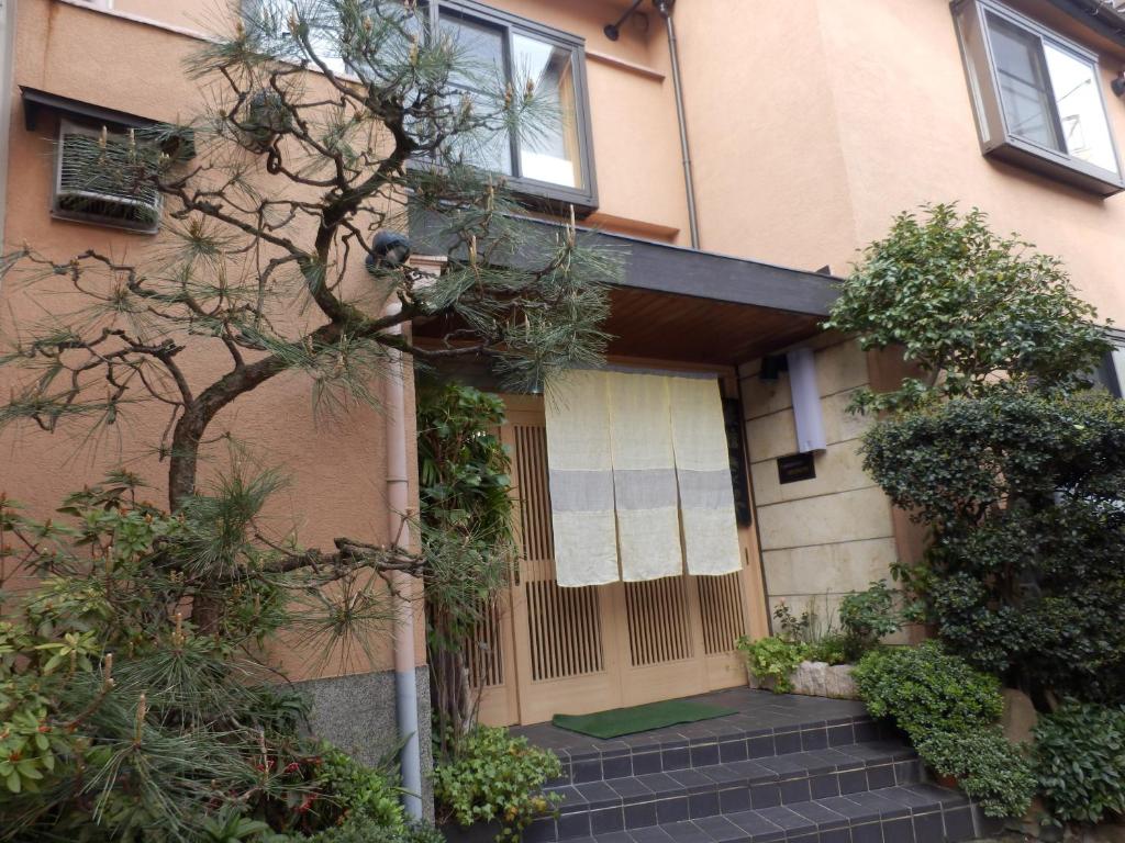 un edificio con un árbol delante de él en Kikunoya Ryokan, en Kanazawa