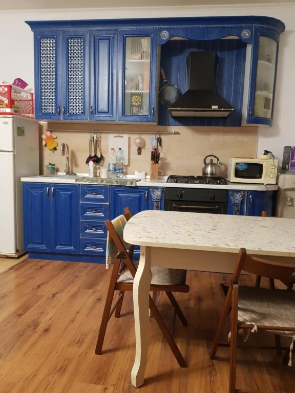 a kitchen with blue cabinets and a table with chairs at Guest house Norilchanka in Gelendzhik
