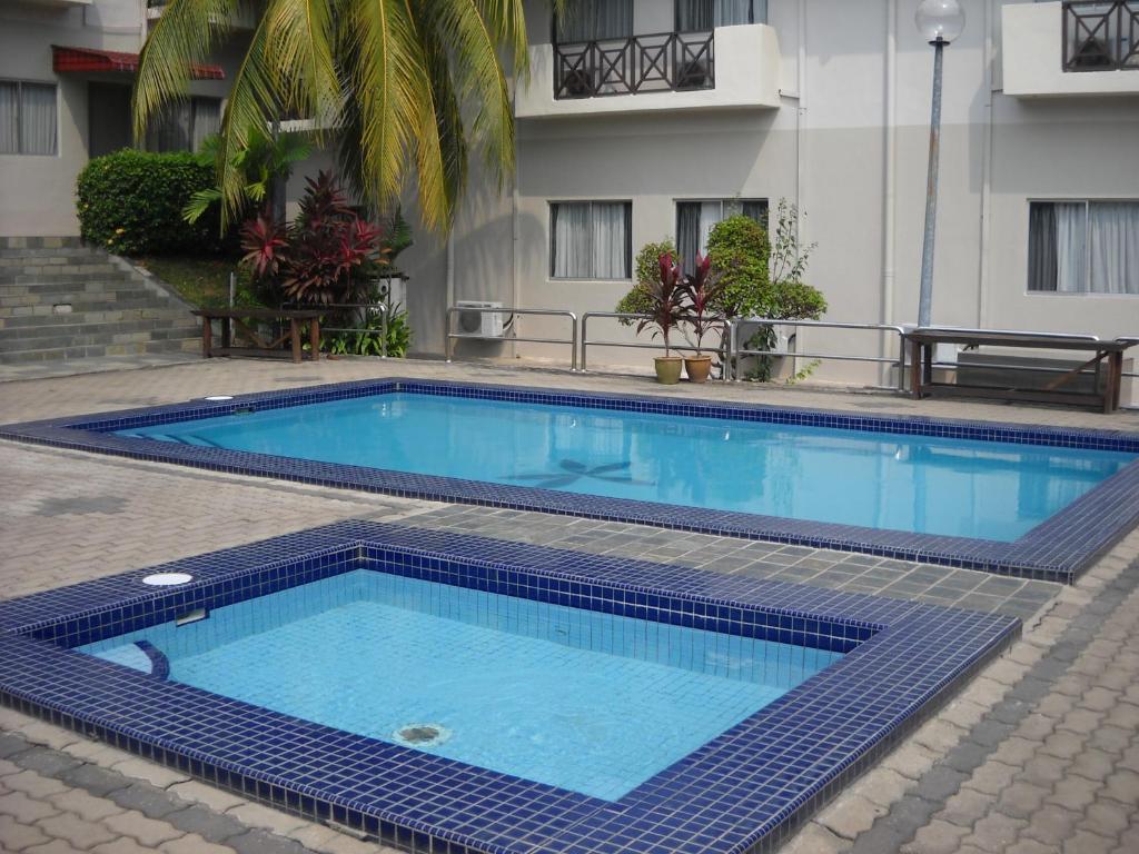 a large blue swimming pool next to a building at Hotel Seri Malaysia Port Dickson in Port Dickson