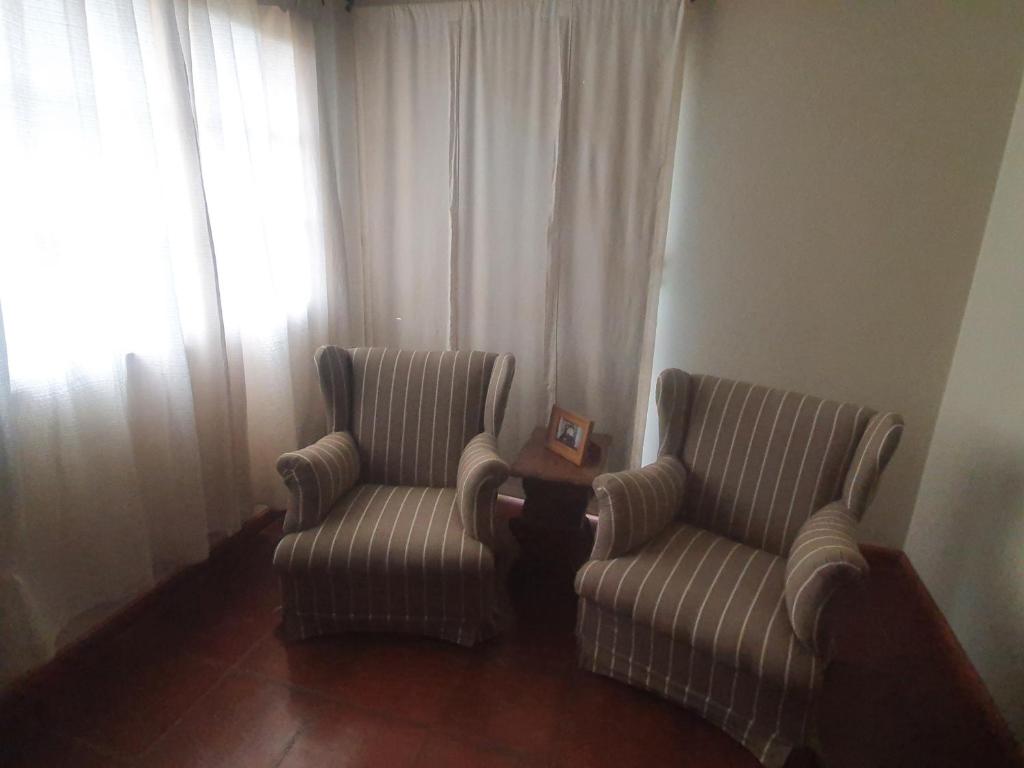 two chairs in a living room with curtains at Casa Astoria in San Pedro