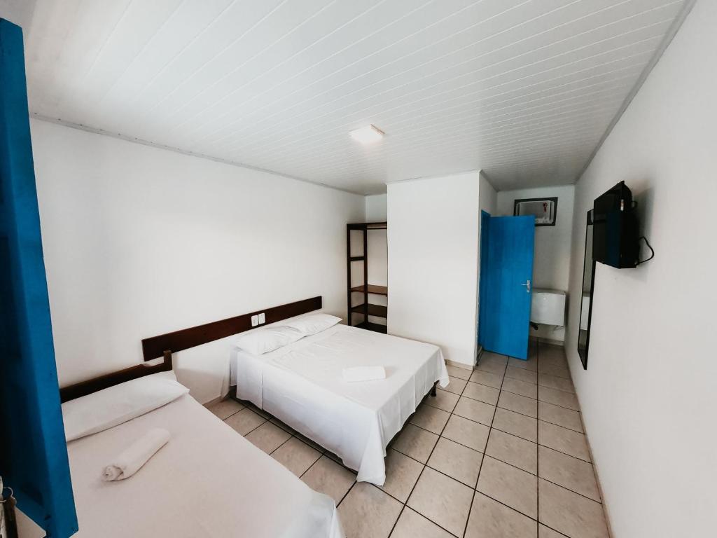 Habitación pequeña con 2 camas y TV. en Pousada Aluá, en Porto Seguro
