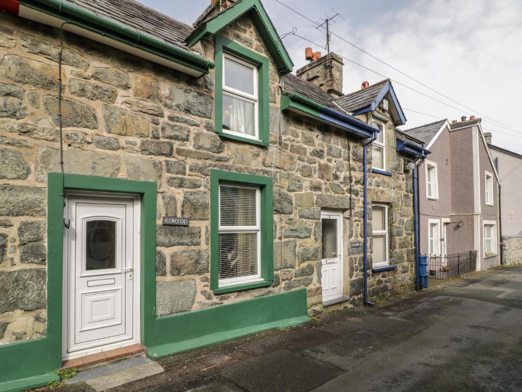 an old stone house with green shutters on a street at Edrydd in Harlech