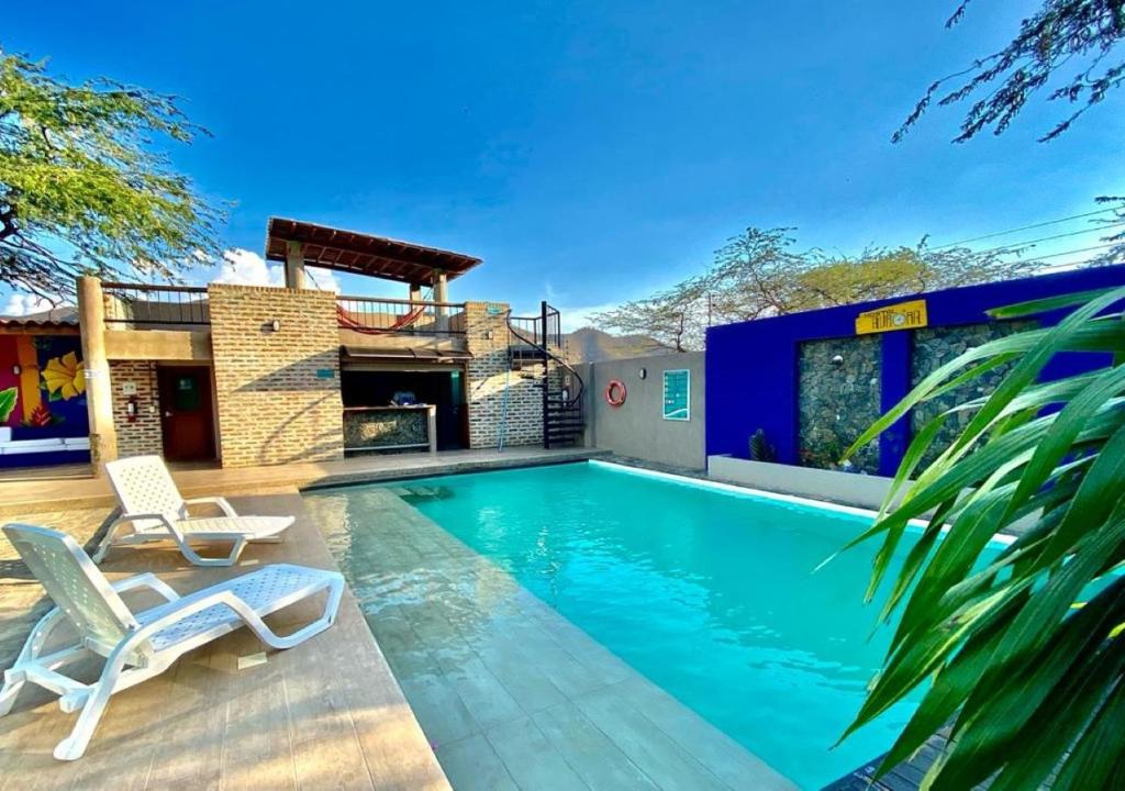 a swimming pool with two chairs and a house at Hostal Aurora, Smith Lodging in Taganga
