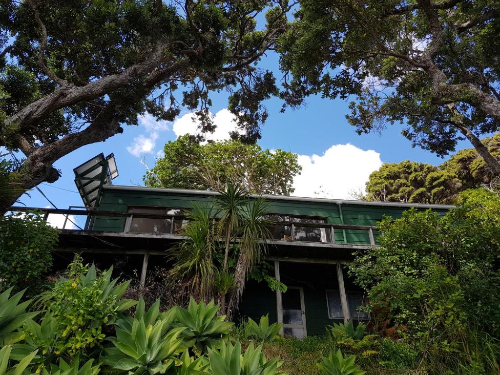 a green house in the middle of trees at Awesome View Cottage in Great Barrier Island