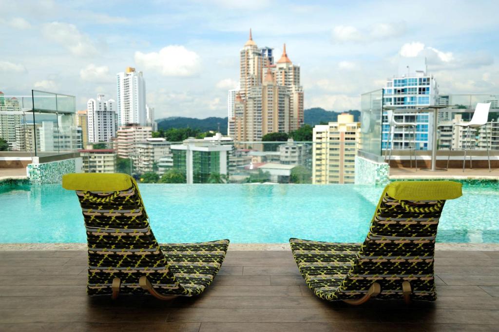 Duas cadeiras sentadas numa varanda com vista para a cidade em Best Western Plus Panama Zen Hotel na Cidade do Panamá