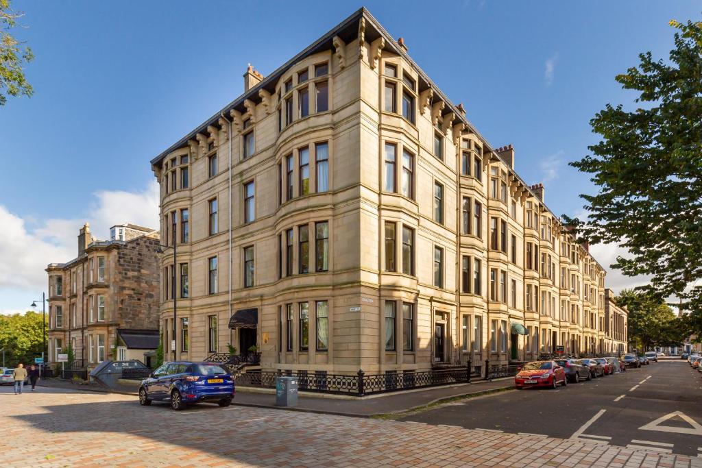 un gran edificio con coches estacionados frente a él en The Alamo Guest House, en Glasgow