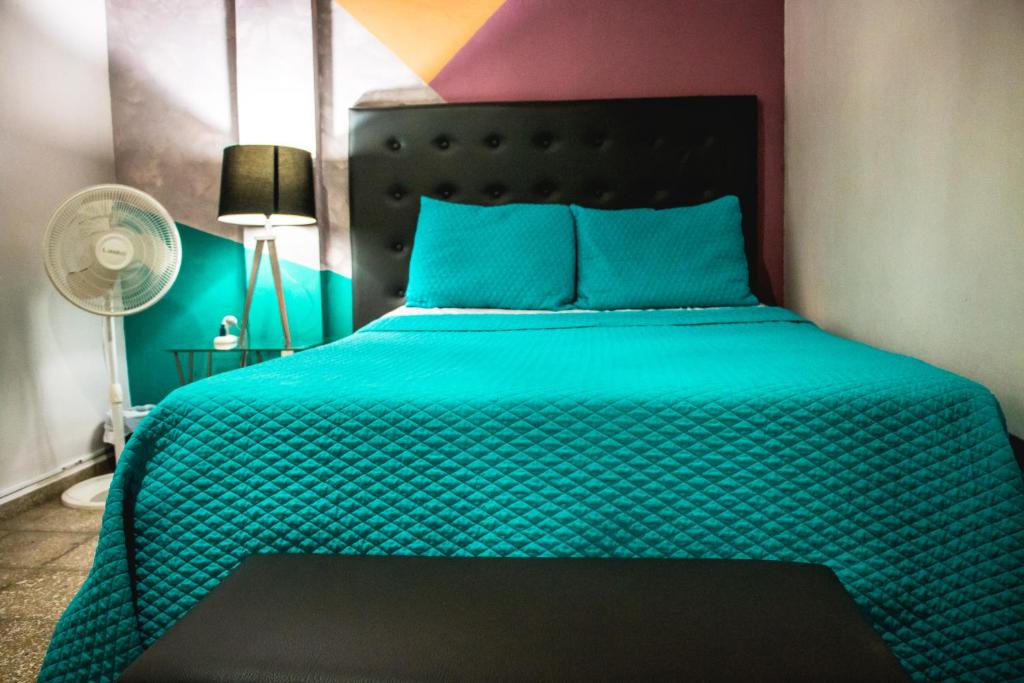 ein Schlafzimmer mit einem Bett mit einer grünen Bettdecke in der Unterkunft Hostal Sole in Santa Ana