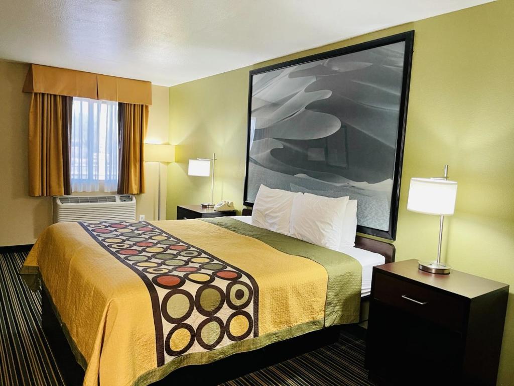 a hotel room with a bed and a large painting on the wall at Super 8 by Wyndham Casa Grande in Casa Grande