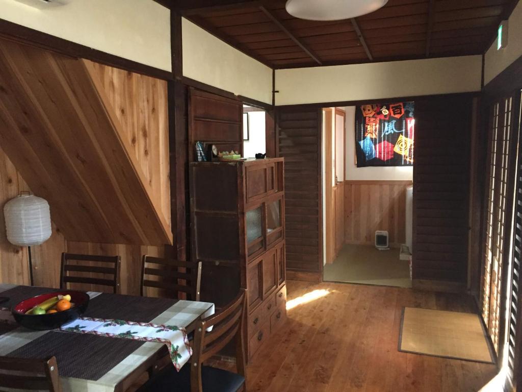 a dining room with a table and a kitchen with wooden walls at Munetada House in Kyoto