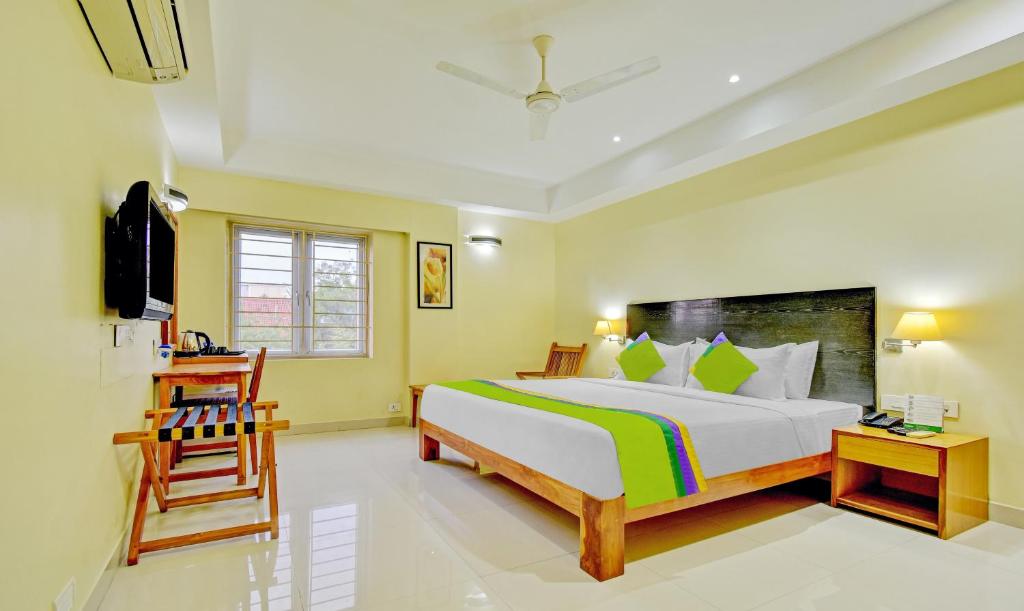 um quarto com uma cama grande e uma cadeira em Treebo Trend Vapr Guindy Ekkatuthangal em Chennai