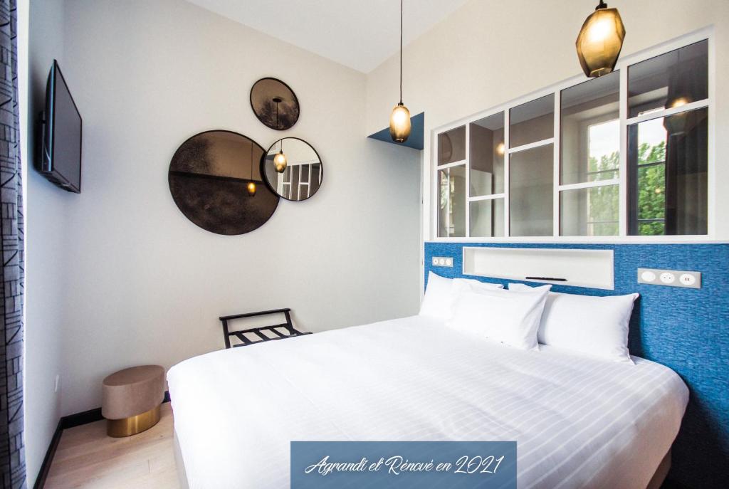 a bedroom with a bed and a clock on the wall at Logis Villa C Hôtel in Bourges