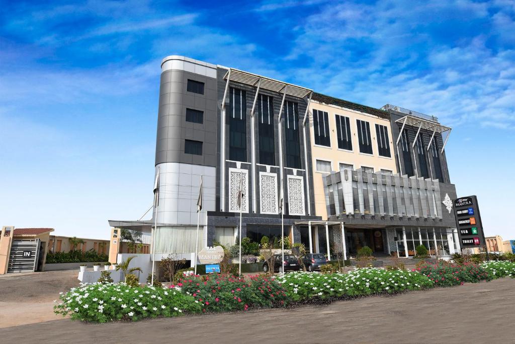 a large white building with flowers in front of it at Pal Heights Mantra in Bhubaneshwar