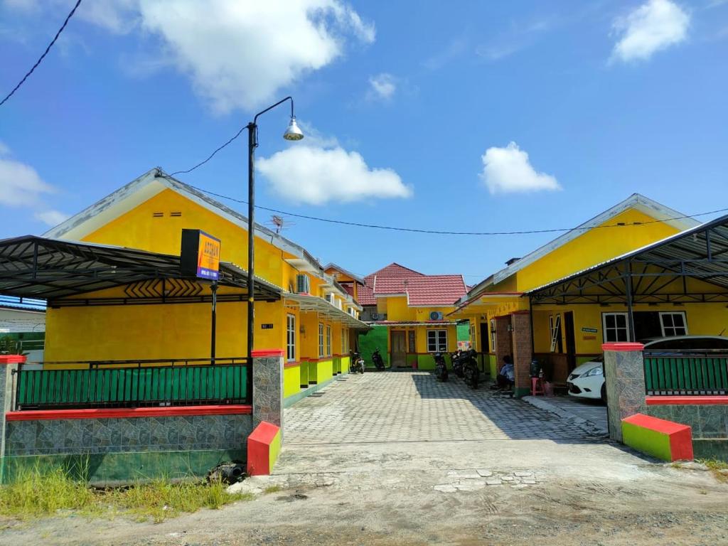 a group of buildings with yellow and green at Adihan Homestay Mitra RedDoorz in Palangkaraya