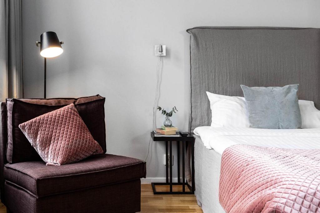 a bedroom with a bed and a chair and a lamp at Biz Apartment Gärdet in Stockholm