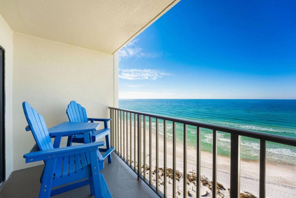2 sillas azules en un balcón con vistas al océano en Commodore 802, en Panama City Beach