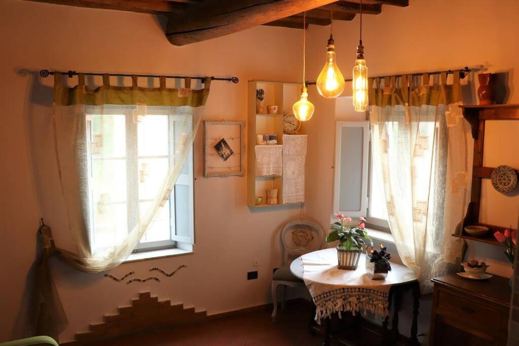 een eetkamer met een tafel en twee ramen bij Antiche Fonti in Bibbona