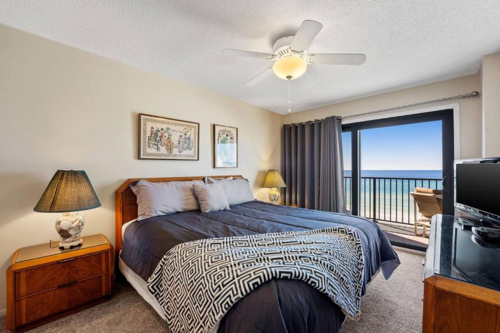 um quarto com uma cama e uma varanda com o oceano em Commodore 502 em Panama City Beach