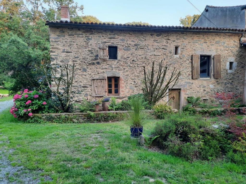 an old stone house with flowers in the yard at Gîte du Petit Moulin in Réaumur