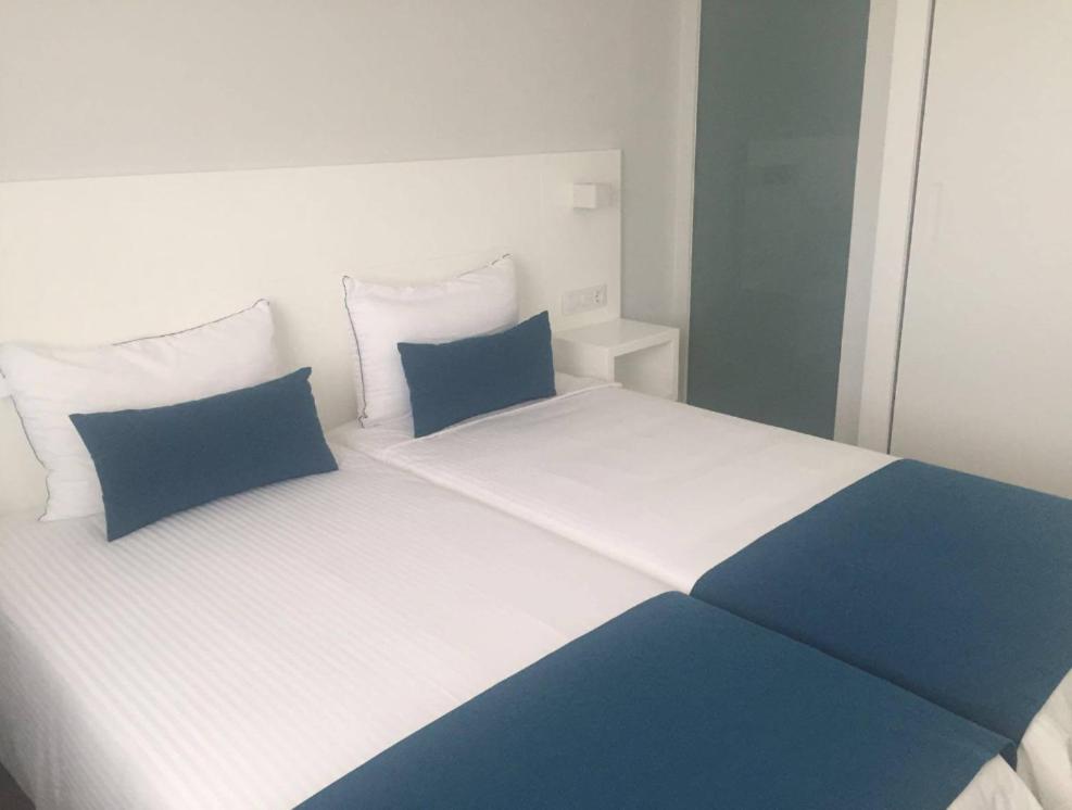 uma cama branca e azul com almofadas azuis em Puerto Príncipe em Puerto Rico de Gran Canaria