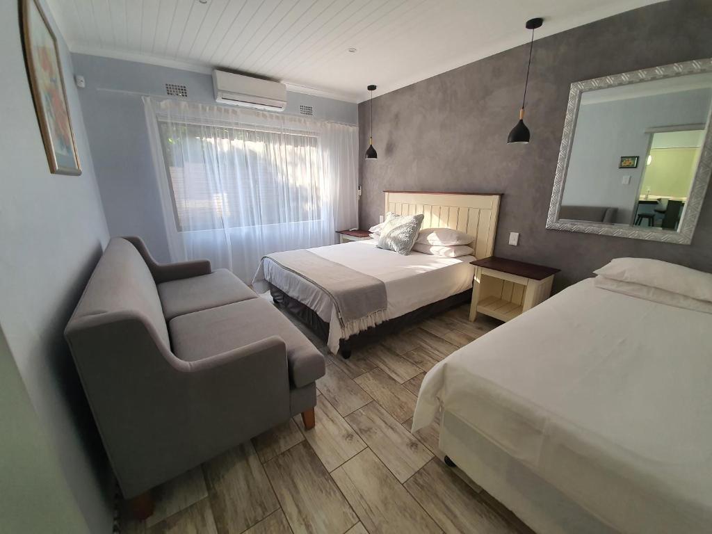 een slaapkamer met 2 bedden, een bank en een spiegel bij Guest house on Gillian Unit 1 in Ballito