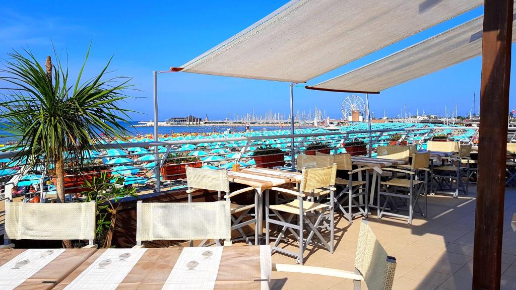 een restaurant met tafels en stoelen en een strand bij Hotel Paloma in Rimini