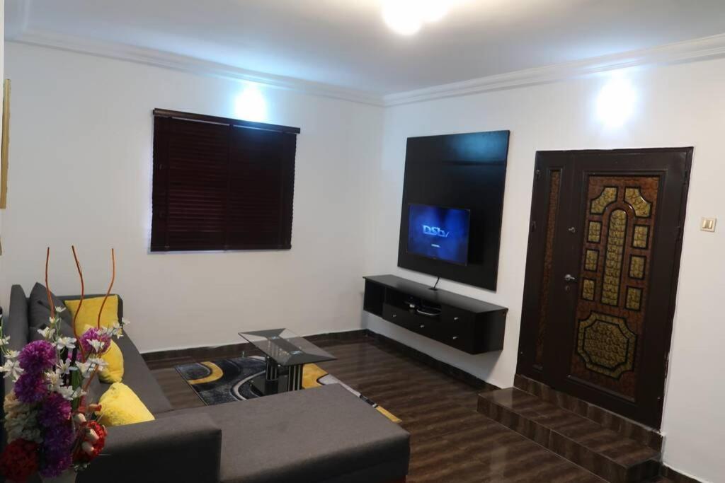 sala de estar con sofá y TV de pantalla plana en KALMS APARTMENT, en Port Harcourt