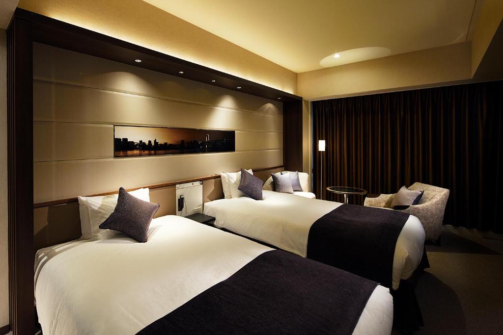 a hotel room with two beds and a chair at Solaria Nishitetsu Hotel Ginza in Tokyo
