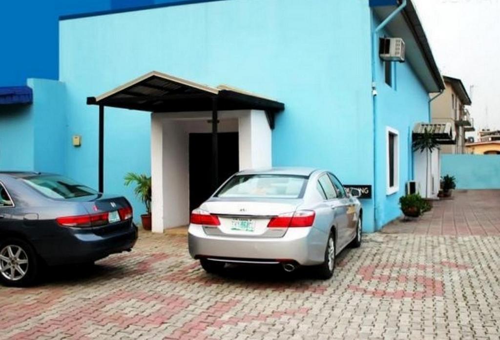 two cars parked in front of a blue building at Room in Lodge - Eaglespark1960 Hotel in Ikeja