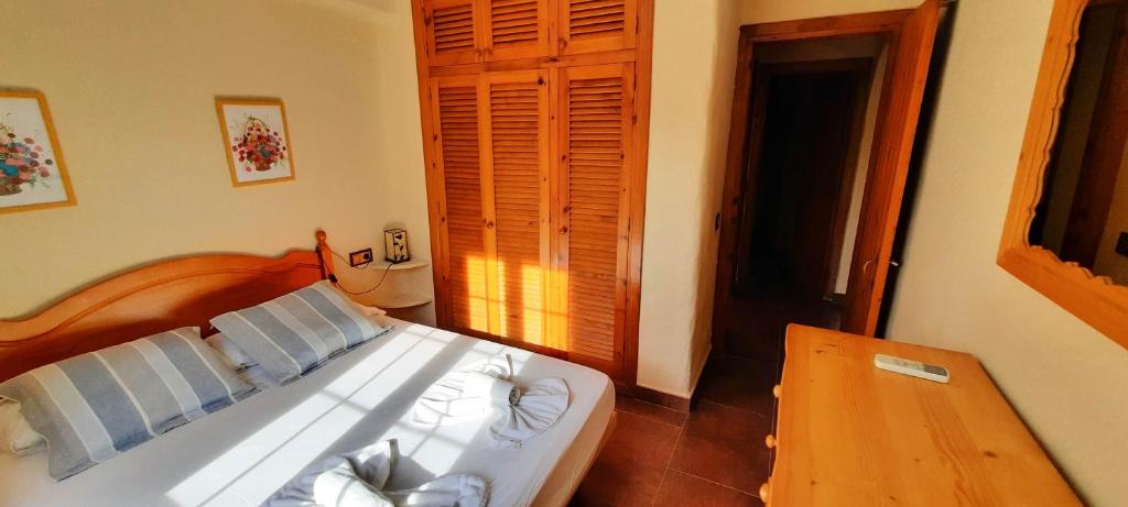 sypialnia z białym łóżkiem i drewnianym stołem w obiekcie Homenfun Menorca Playa de Fornells I w mieście Fornells