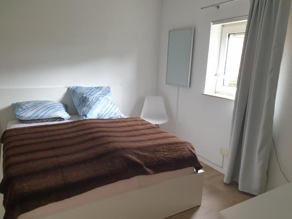 a bedroom with a bed with a brown blanket and a window at Am Schloss in Angelbachtal