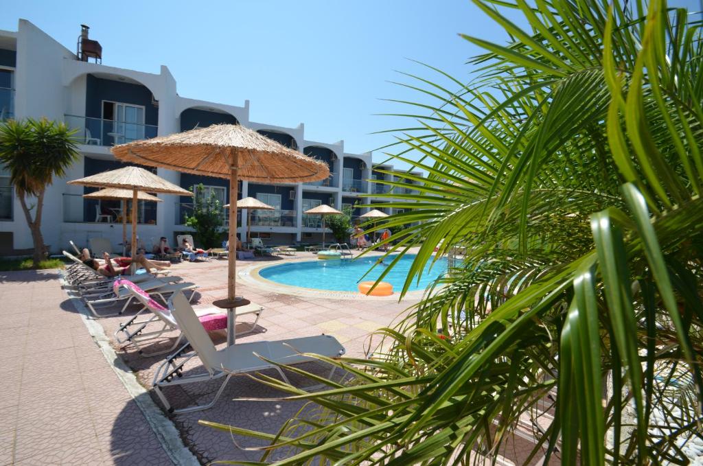 a resort with a pool with chairs and umbrellas at Sevastos Studios in Faliraki
