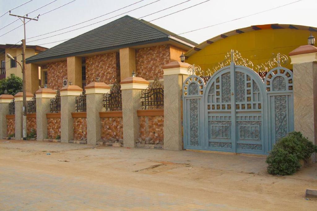 a house with a blue gate and a fence at Room in Lodge - Owees Place-okota in Lagos