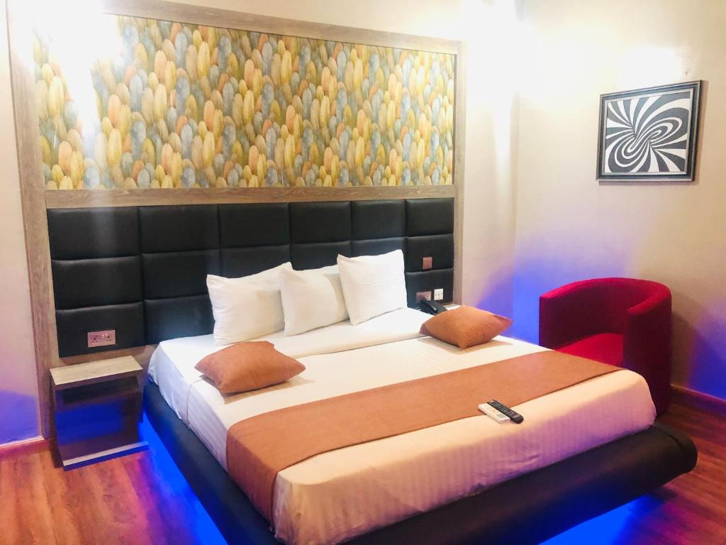 a bedroom with a large bed with a painting on the wall at Mayor's & Diplomat Suite in Ikeja