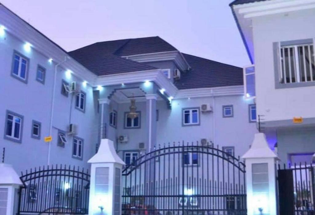 a large white building with a gate and lights at Room in Lodge - Seth Hotel Asaba in Asaba