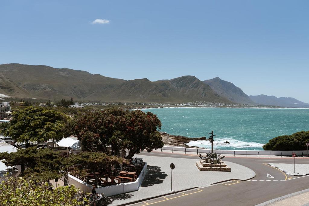 a road next to a beach with mountains in the background at Auberge Burgundy Boutique Hotel & Spa in Hermanus