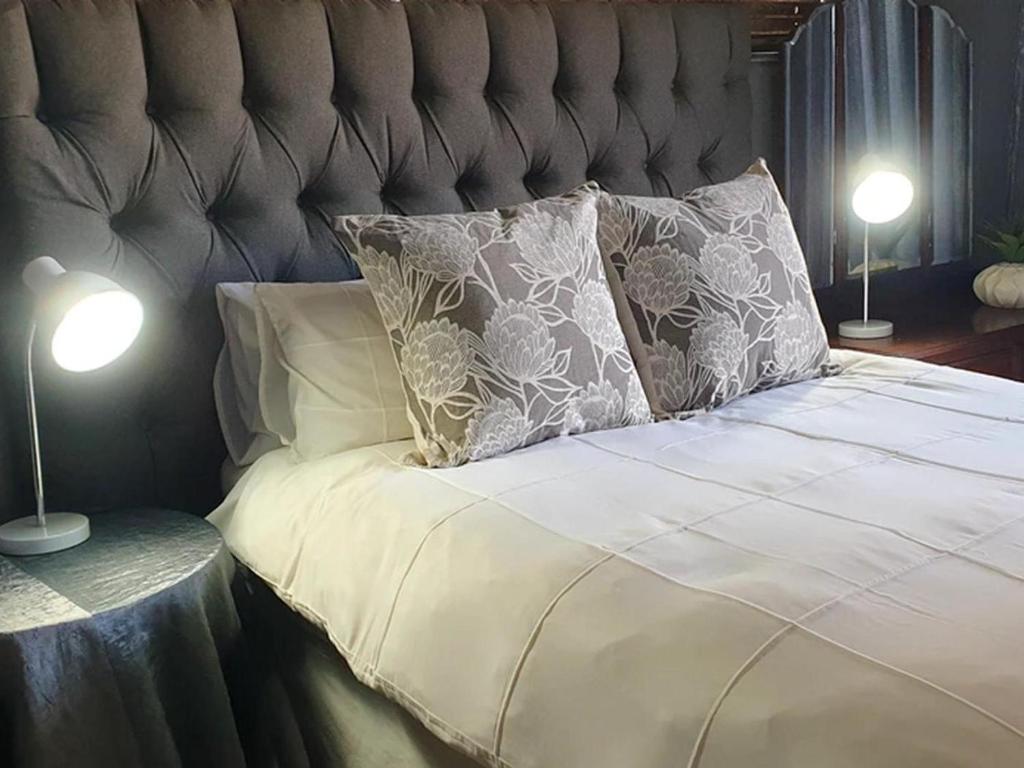1 cama con 2 almohadas y 2 lámparas en Rand Self-catering Accommodation, en Carolina