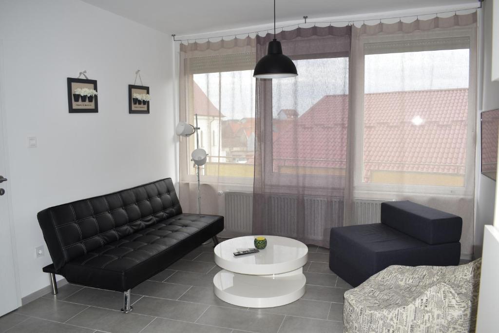 - un salon avec un canapé noir et une table dans l'établissement Apartman WALKOW, à Vukovar