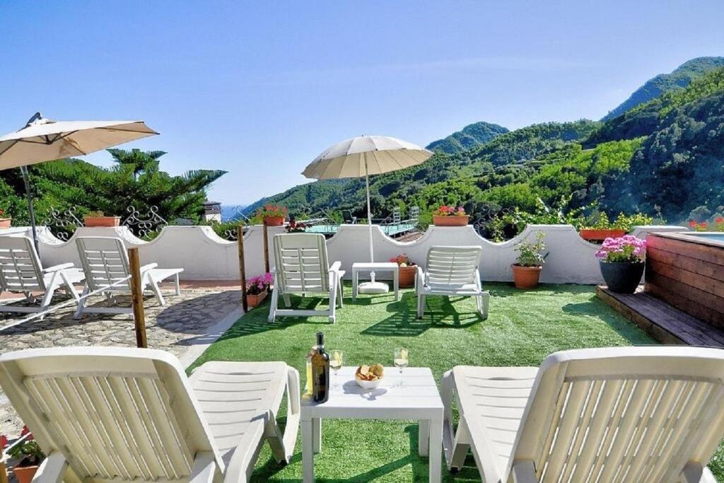 un patio con sedie e tavoli bianchi e ombrellone di Villa Inn Costa a Tramonti