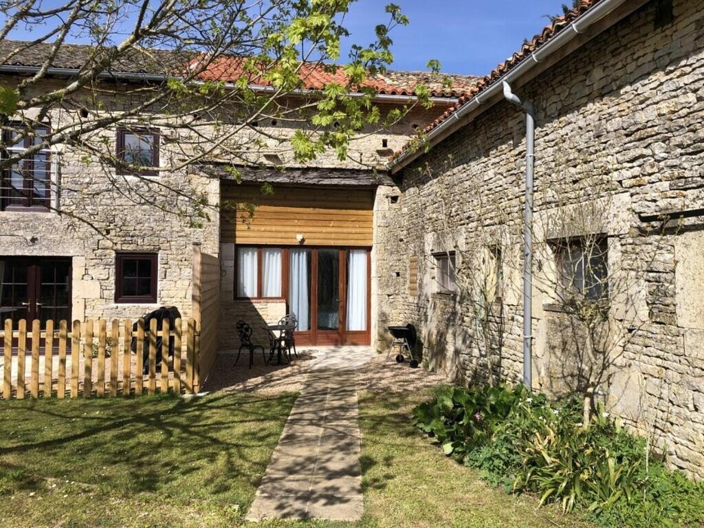 une maison en pierre avec une porte en bois et une clôture dans l'établissement Blacksmiths Apartment in Blanzay - 1 bed, à Blanzay