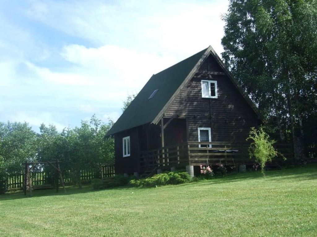 a large wooden barn with a gambrel roof on a field at Domek letniskowy nad Jez. Dadaj in Biskupiec
