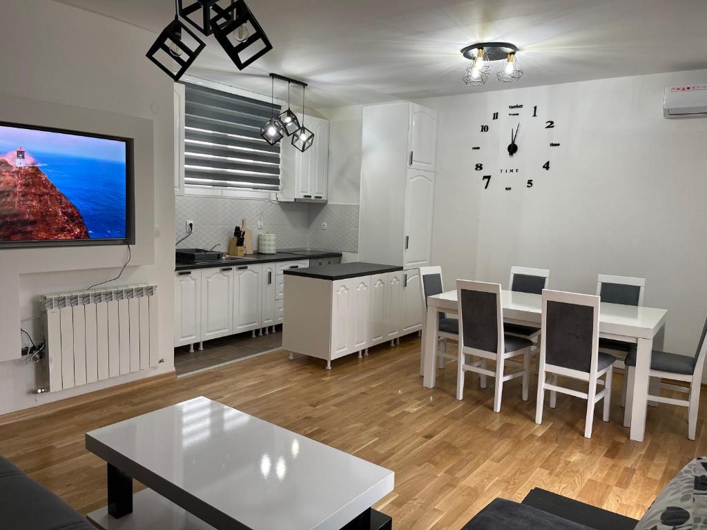 a living room with a table and a clock on the wall at Royal Residence Apartmani 2 in Pančevo