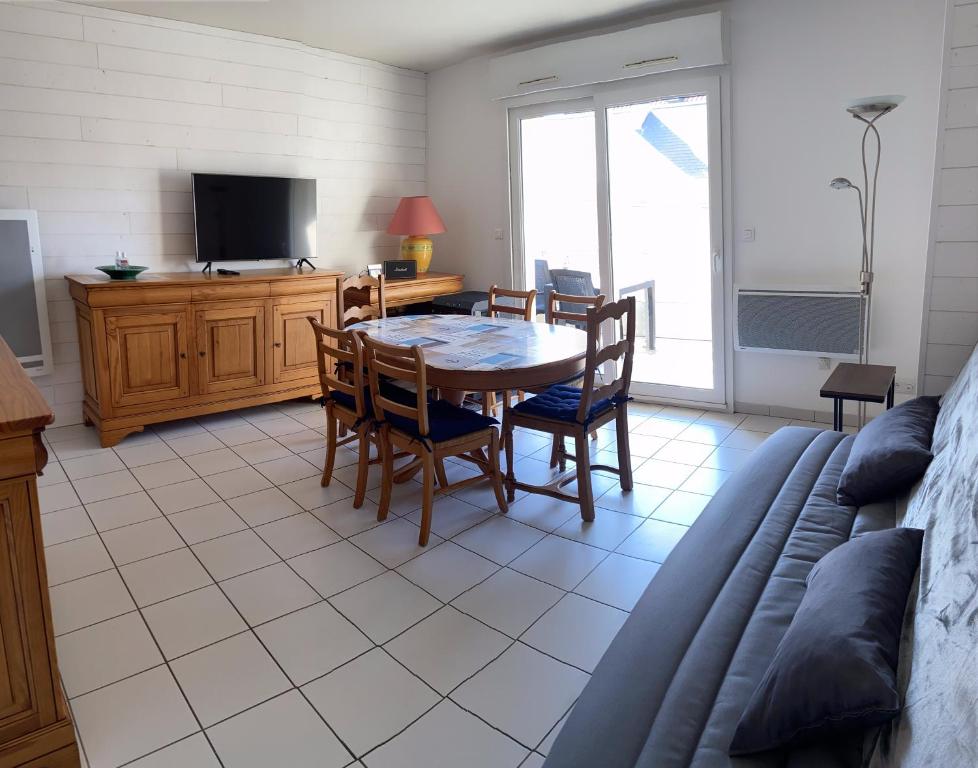 sala de estar con mesa, sillas y TV en L'Aéroplage, Appartement Standing Rénové Vacances 40mètres plage, en Berck-sur-Mer