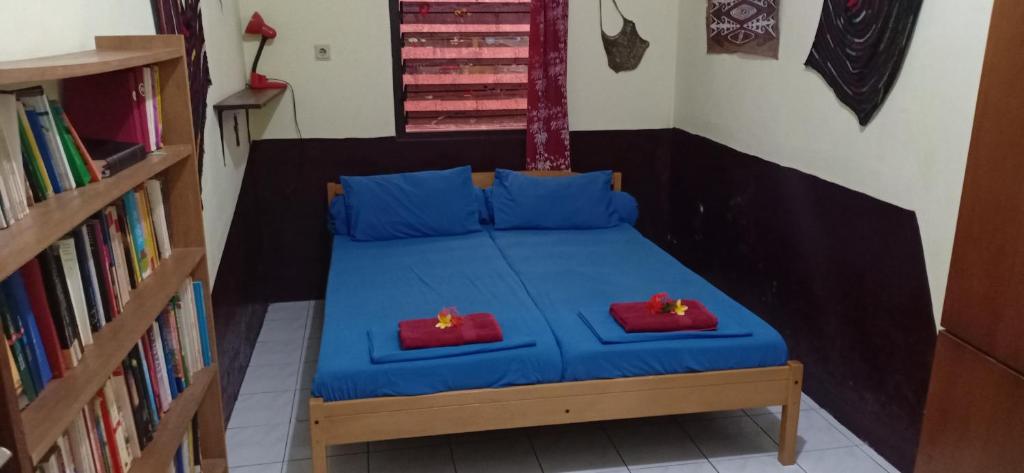 a bedroom with a blue bed with two red pillows at Homestay Galpera Papua in Jayapura