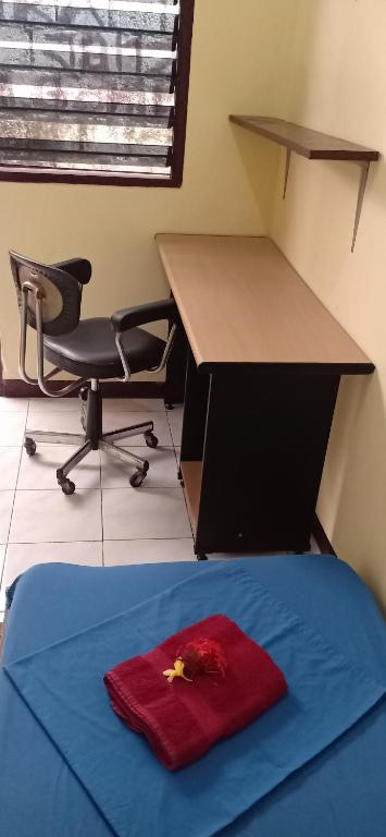 a desk and a bed with a red towel on it at Homestay Galpera Papua in Jayapura